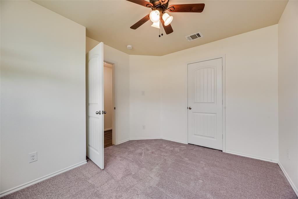 Neutral interior space featuring wall-to-wall carpeting, an arched-panel interior door, and a multi-light ceiling fan