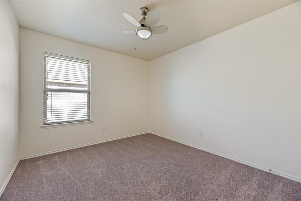Neutral-toned carpeted flooring, window with installed horizontal blinds, and a multi-blade ceiling fan with integrated light fixture