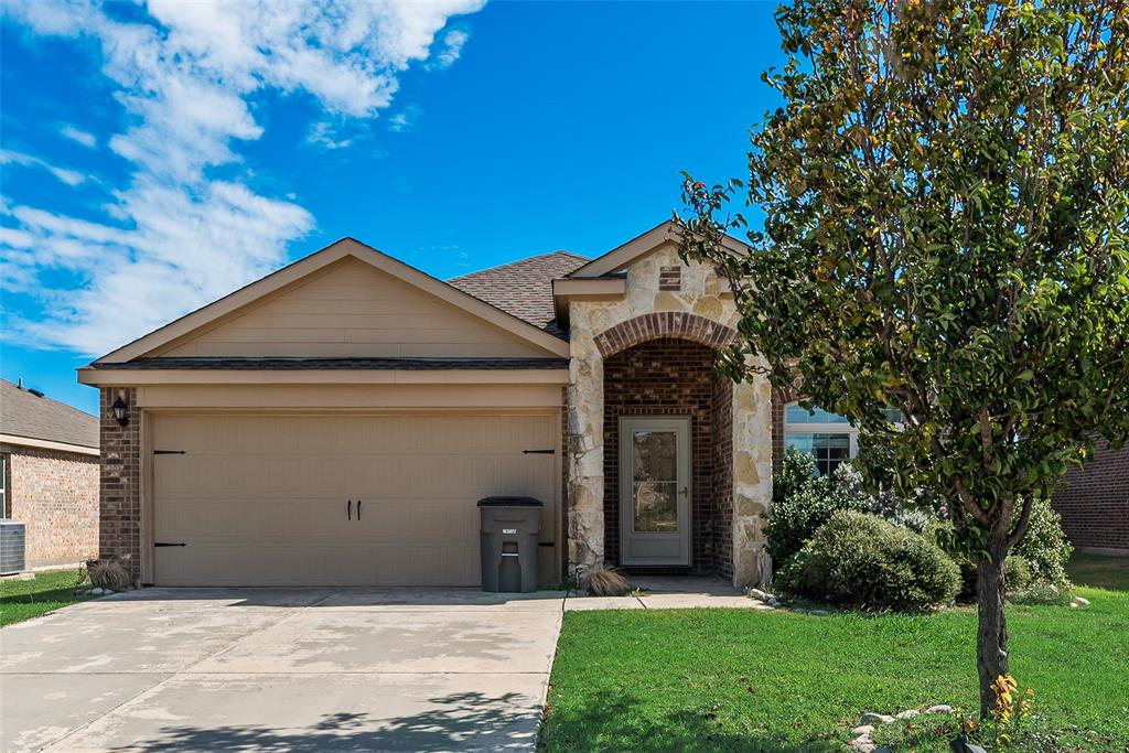 Single-story exterior featuring a stone and brick facade, arched entryway, and two-car garage