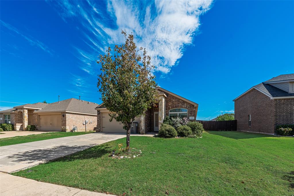Brick exterior with stone accents, arched window detailing, concrete driveway, and covered entryway