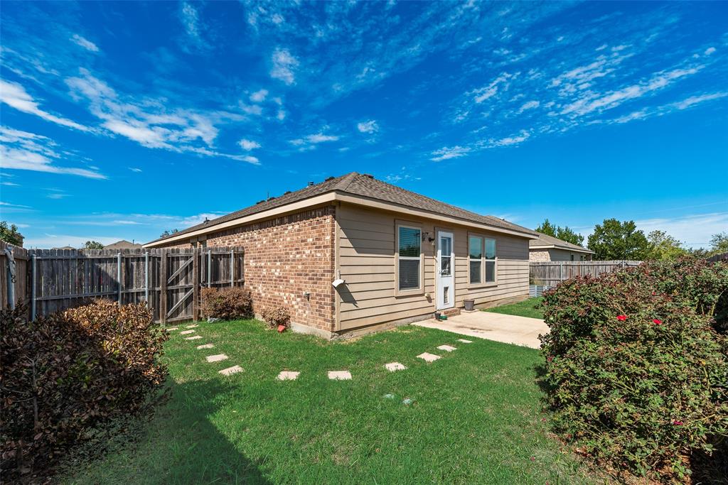 Rear exterior featuring a brick and horizontal siding facade, concrete patio, stepping stone pathway, and wood privacy fencing
