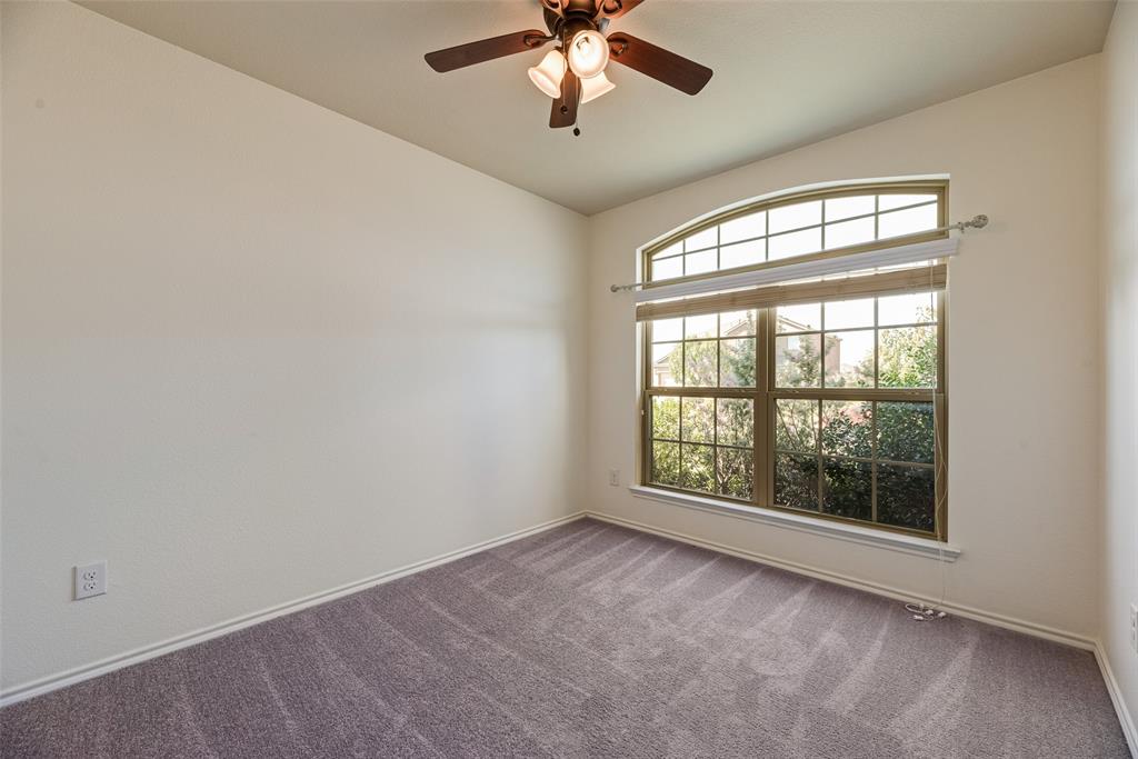 Arched window with grid detailing, neutral carpeting, ceiling fan with integrated lighting, and off-white wall finish
