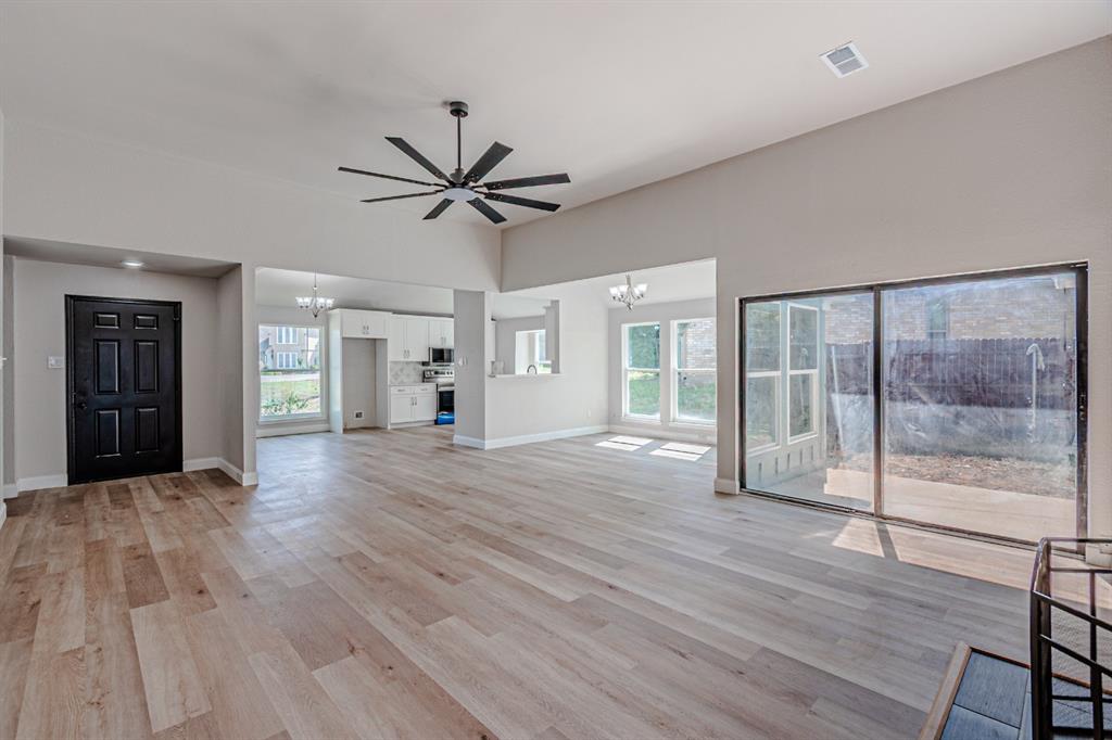Vaulted ceiling, wood-finish flooring, multi-blade ceiling fan, sliding glass door, and recessed lighting