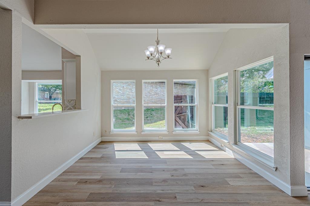 Vaulted ceiling with a five-light chandelier, wood-finish flooring, and expansive windows