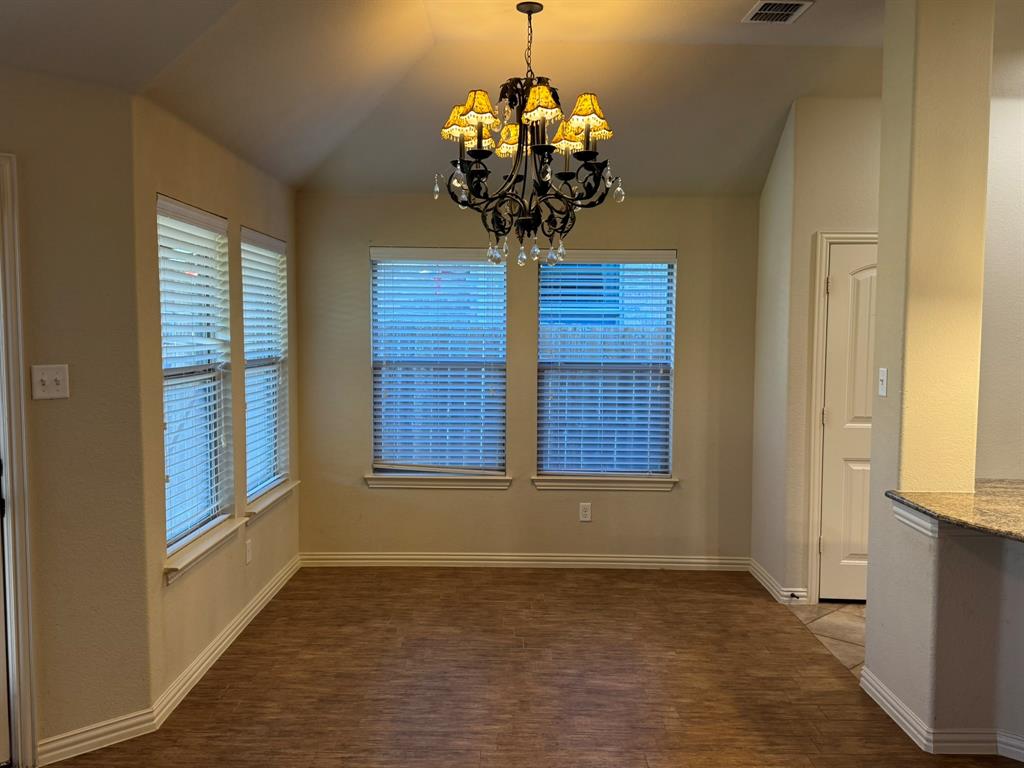 Vaulted ceiling, wood-finish flooring, multi-pane windows with horizontal blinds, and a traditional tiered chandelier
