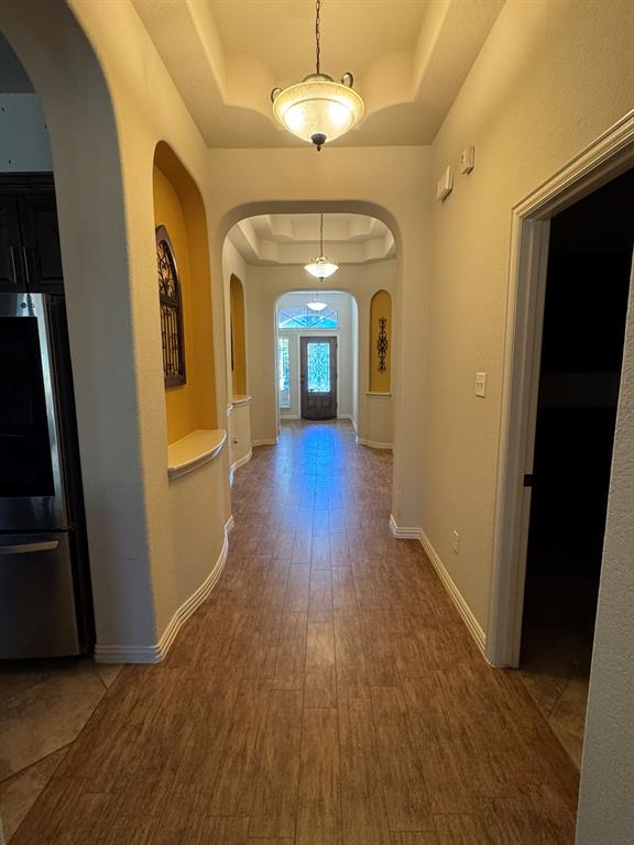 Entryway featuring wood-finish flooring, recessed ceilings, arched architectural alcoves, and decorative pendant lighting