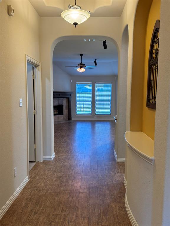 Entryway featuring wood-finish flooring, an arched architectural alcove with a built-in display shelf, a recessed ceiling tray, and a semi-flush mount light fixture
