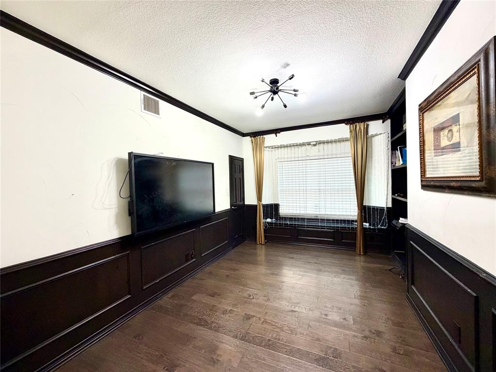 Room featuring wood-finish flooring, dark wainscoting, built-in shelving, a bay window with a window seat, and a modern sputnik-style chandelier