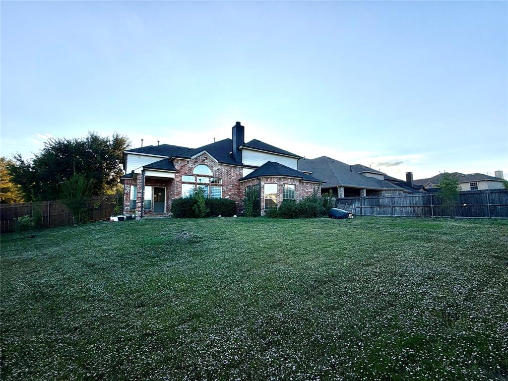 Brick exterior featuring multi-gabled rooflines, arched window detailing, and a spacious rear yard enclosed by wood privacy fencing