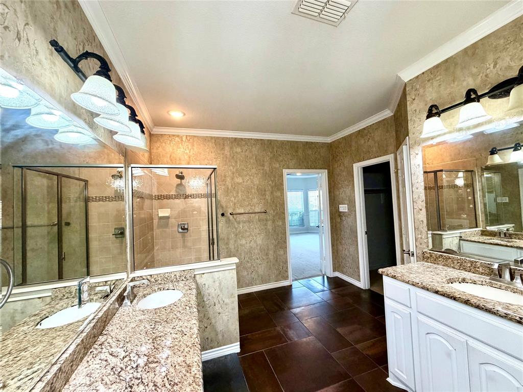 Dual-vanity bathroom featuring stone-look countertops, white cabinetry, large plate glass mirrors with multi-light wall fixtures, and a glass-enclosed shower with tile surrounds, finished with oversized tile flooring