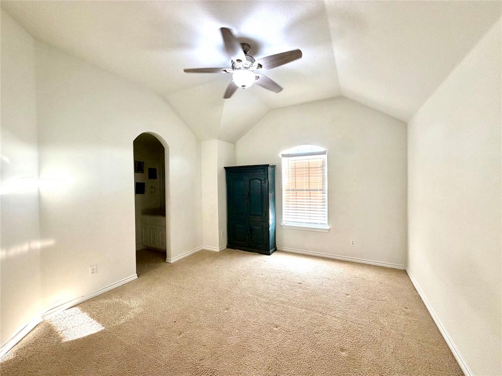 Vaulted ceiling featuring an arched doorway and a central ceiling fan with an integrated light fixture