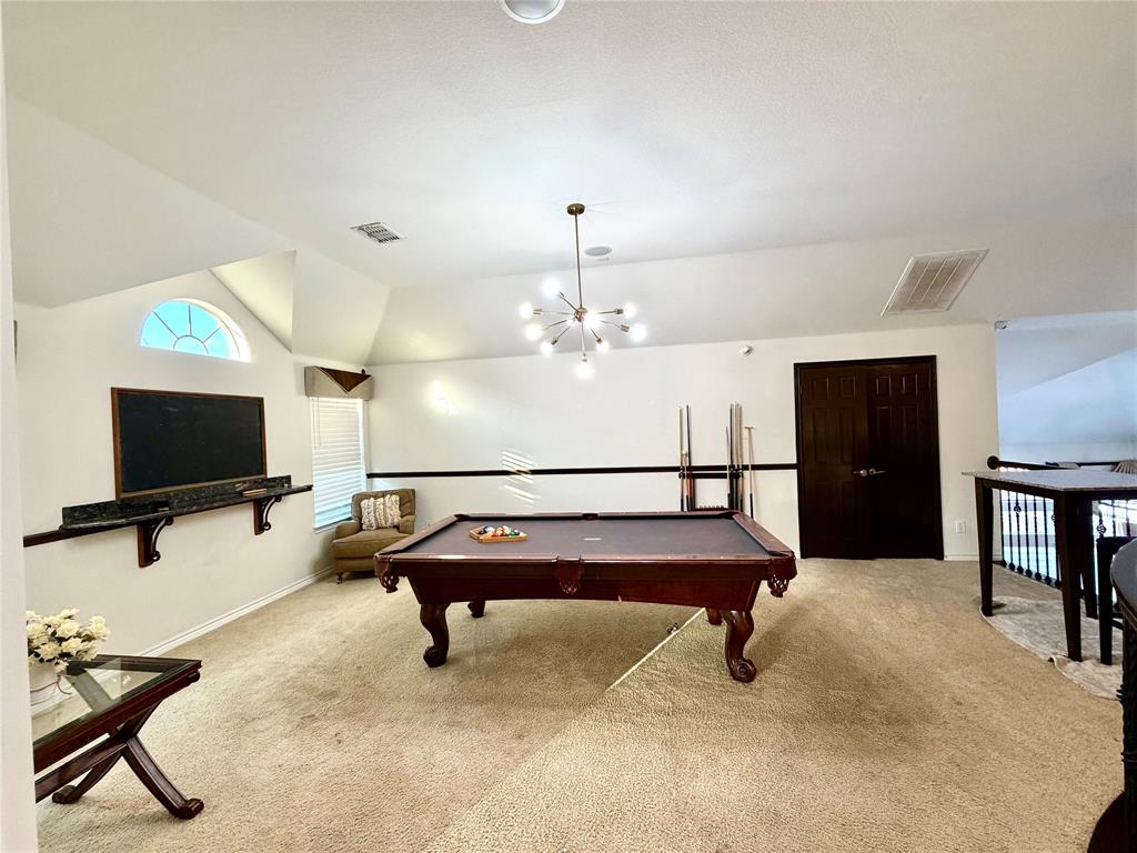 Vaulted ceilings featuring a multi-arm sputnik-style chandelier, arched window, wall-mounted stone shelf, and double-door entry
