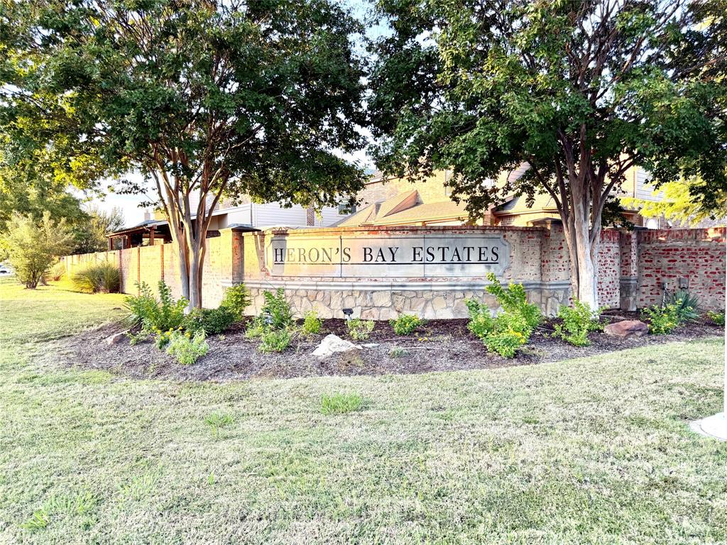 Community entrance signage featuring brick masonry construction, decorative stonework, and mature trees