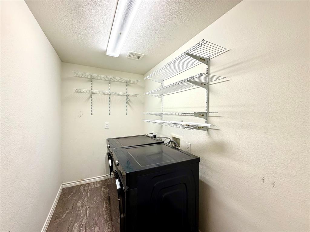 Utility space featuring wood-finish flooring, white wall-mounted wire shelving, and linear flush-mount overhead lighting