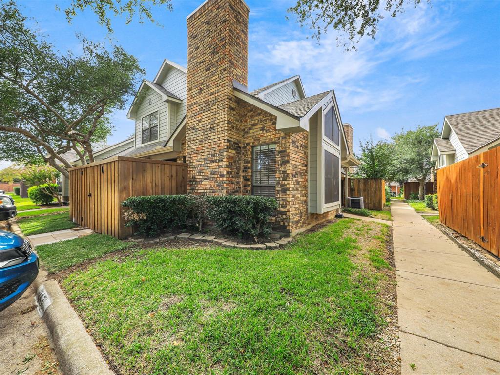 Multi-gabled exterior featuring a prominent full-height brick chimney, horizontal siding, and a concrete walkway