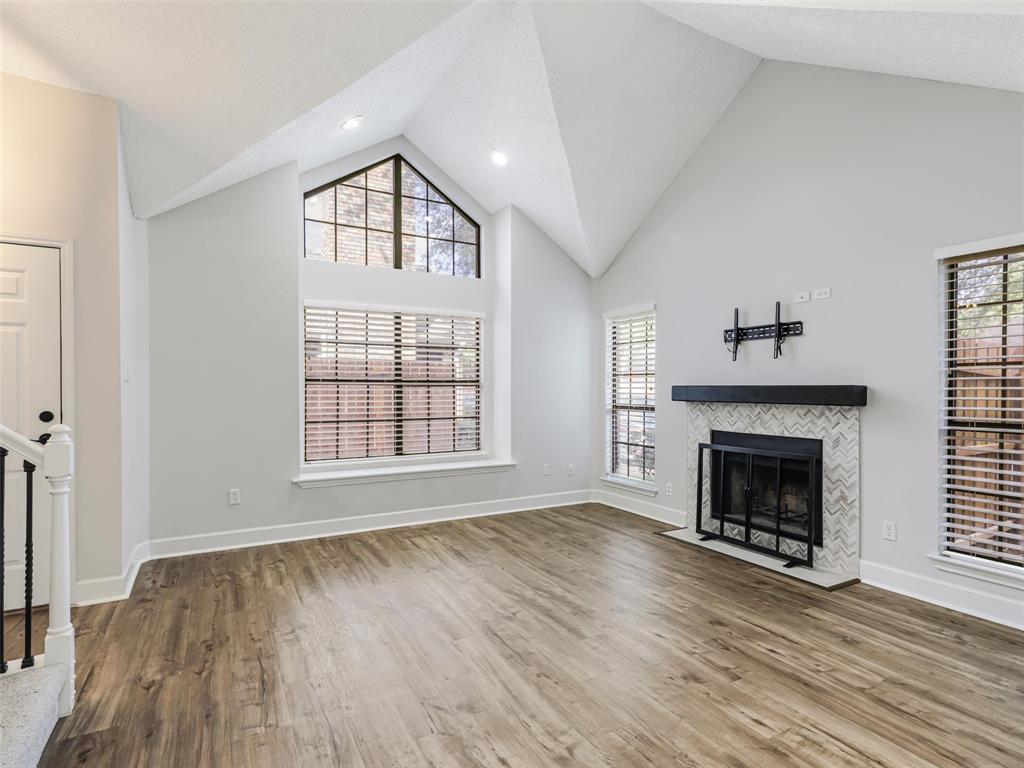 Vaulted ceilings featuring recessed lighting, expansive triangular accent window, fireplace with herringbone tile surround and wood-finish mantel, and wood-finish flooring Vaulted ceilings featuring recessed lighting, expansive triangular accent window, fireplace with herringbone tile surround and wood-finish mantel, and wood-finish flooring