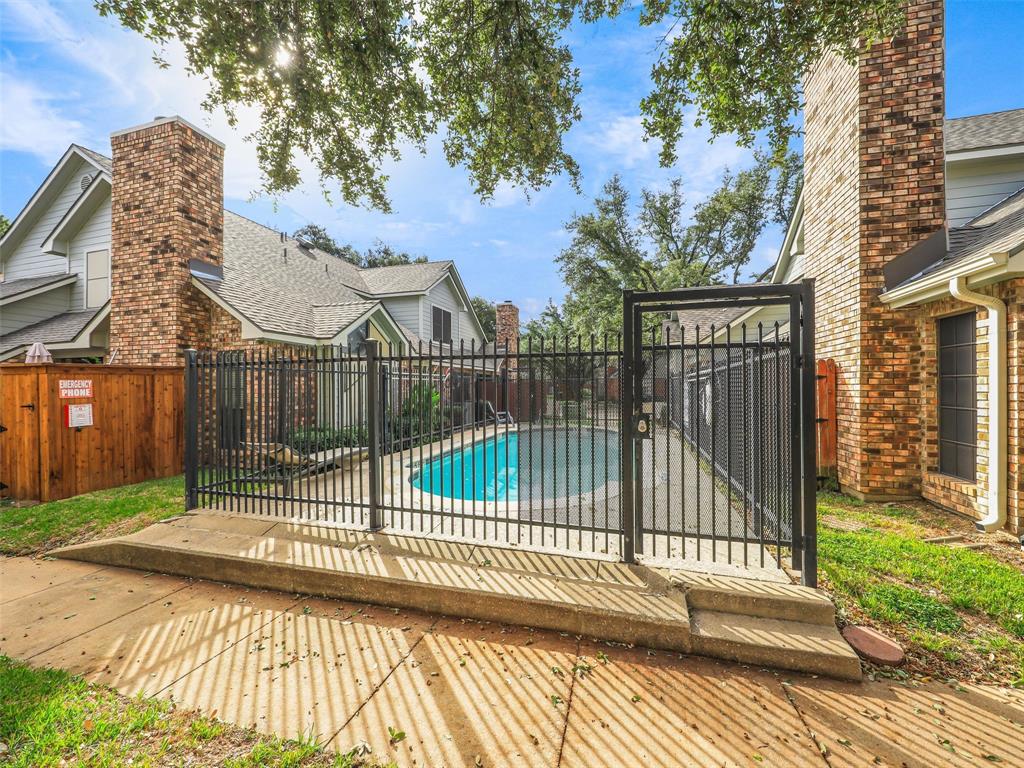 Fenced pool area featuring a concrete deck, brick chimneys, and partial wood privacy fencing