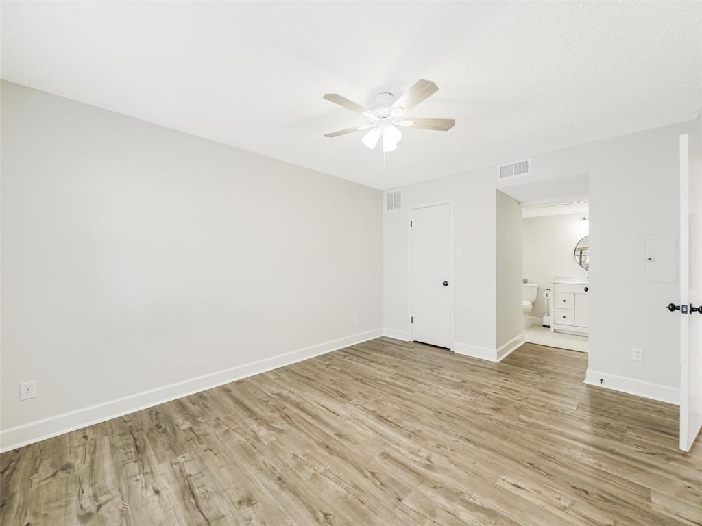 Neutral wall tones, wood-finish flooring, and a ceiling-mounted light fixture with fan