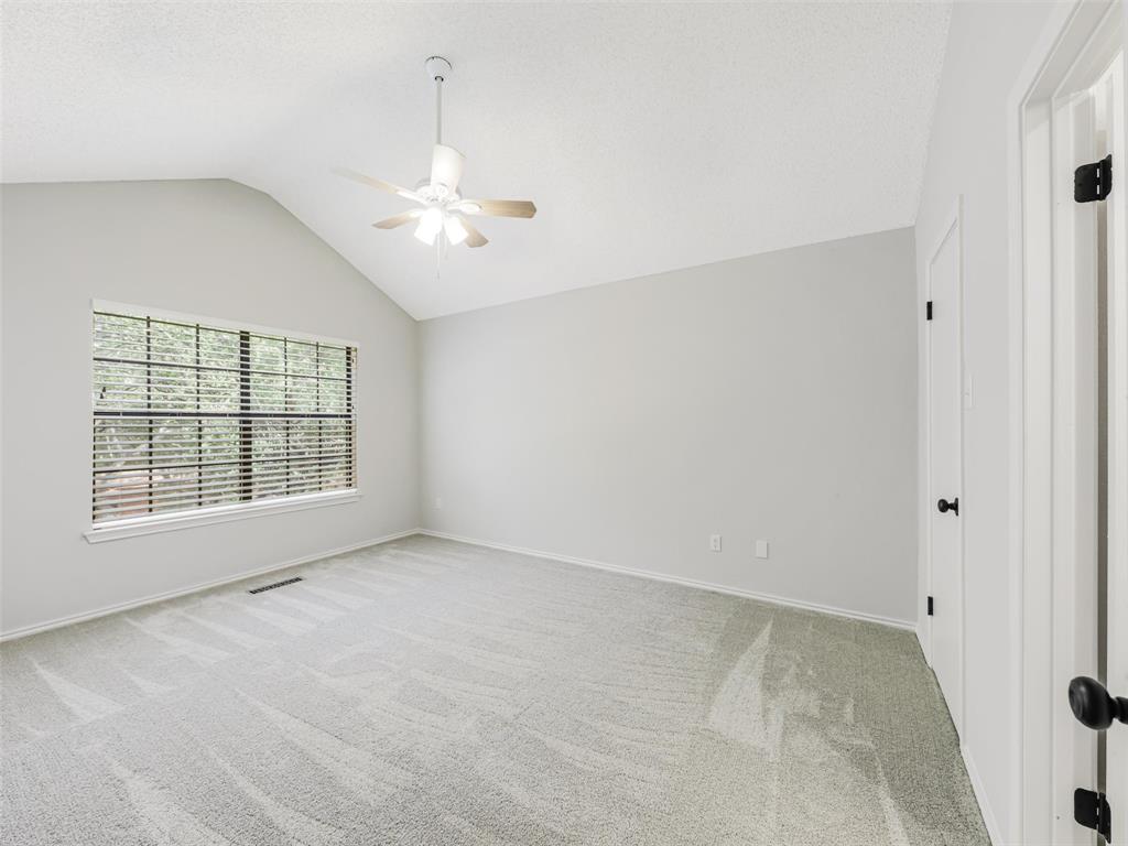 Vaulted ceiling, wall-to-wall carpeting, multi-pane window, and central ceiling fan with integrated lighting