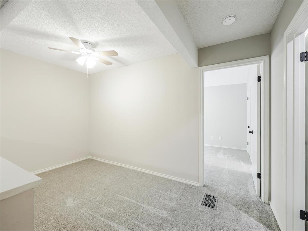 Neutral-toned interior space featuring wall-to-wall carpeting, a ceiling fan with integrated lighting, and a doorway with a hollow-core door