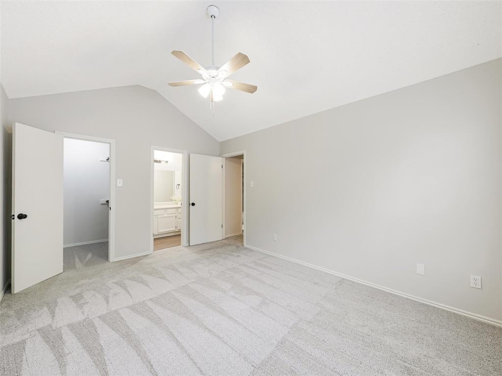Vaulted ceilings featuring a central overhead fan with light fixture, neutral wall finishes, and carpeting