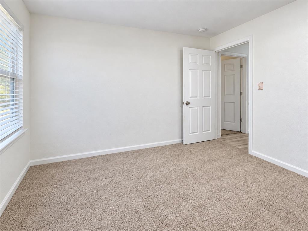 Neutral-toned carpet, white walls, and six-panel interior doors, with white horizontal blinds over the window