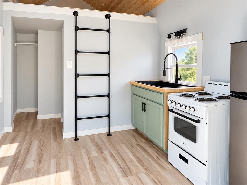 Kitchen area featuring wood-finish flooring, a wall-mounted matte black ladder, light green cabinetry, a wood countertop with a black basin sink, and a white range