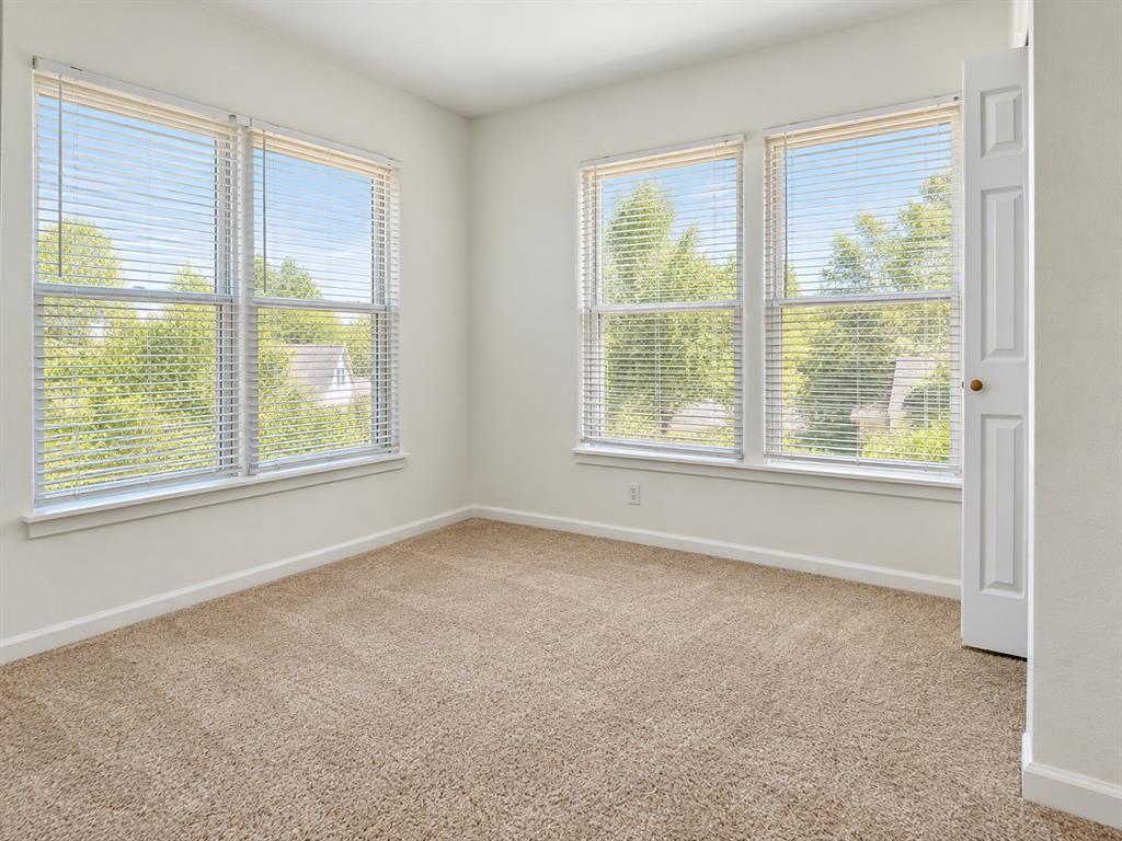 Neutral interior featuring neutral wall paint, wall-to-wall carpeting, and four windows fitted with horizontal blinds