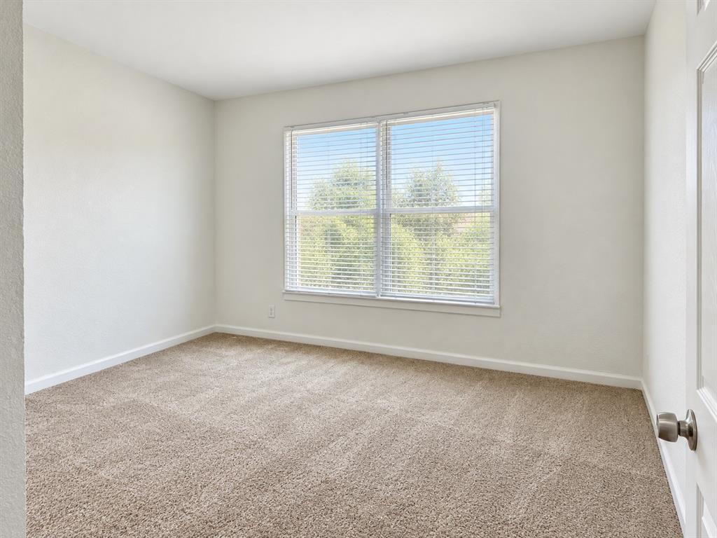 Neutral wall finishes, plush carpeting, a multi-pane window with horizontal blinds, and a solid-core interior door with brushed metal hardware