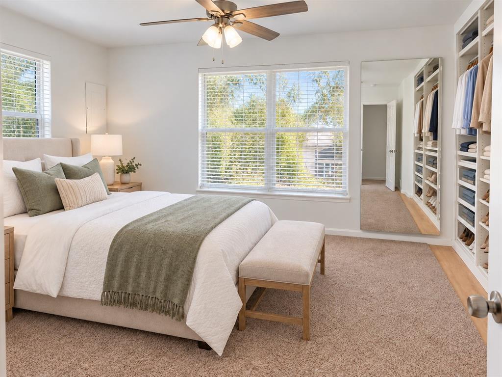 Bedroom featuring wall-to-wall carpeting, custom built-in shelving, a full-length wall mirror, and a ceiling fan with integrated lighting