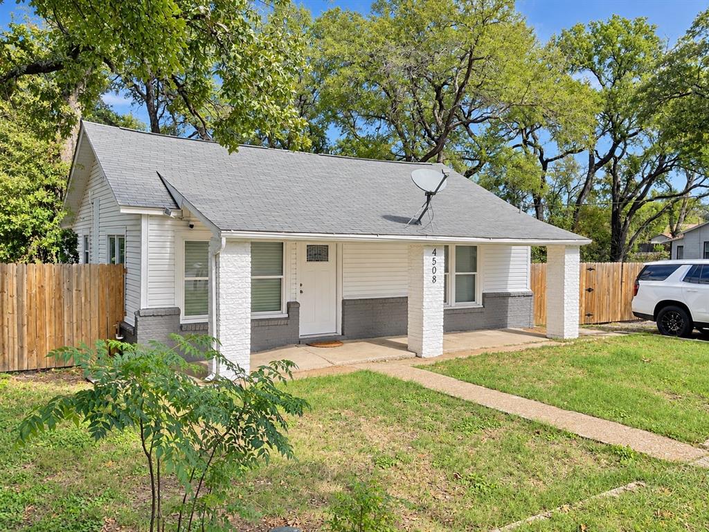 Single-story exterior featuring horizontal siding, a covered front porch with stone-finish pillars, and wood privacy fencing
