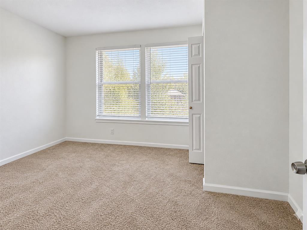 Neutral-toned wall paint, wall-to-wall carpeting, and double-pane windows equipped with horizontal blinds