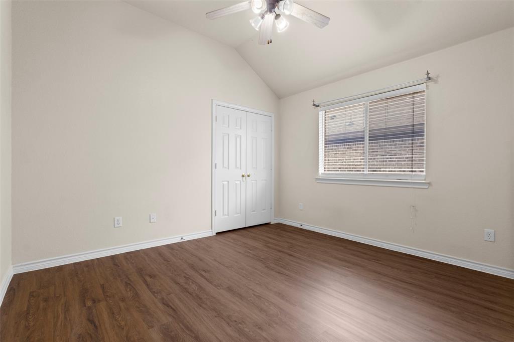 Vaulted ceiling room featuring wood-finish flooring, a white-paneled double-door closet, and a multi-light ceiling fan