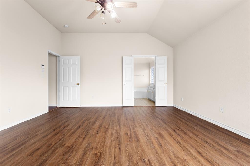 Room featuring vaulted ceilings, wood-finish flooring, a ceiling fan, and white paneled doors