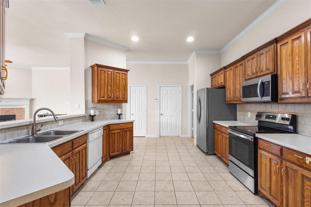 Kitchen featuring stained wood cabinetry, solid surface countertops, tile flooring, recessed lighting, and stainless steel appliances