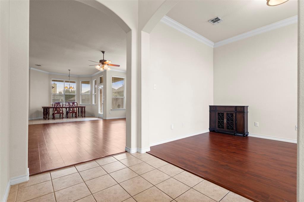 Arched architectural openings, neutral wall palette, crown molding, and wood-finish flooring