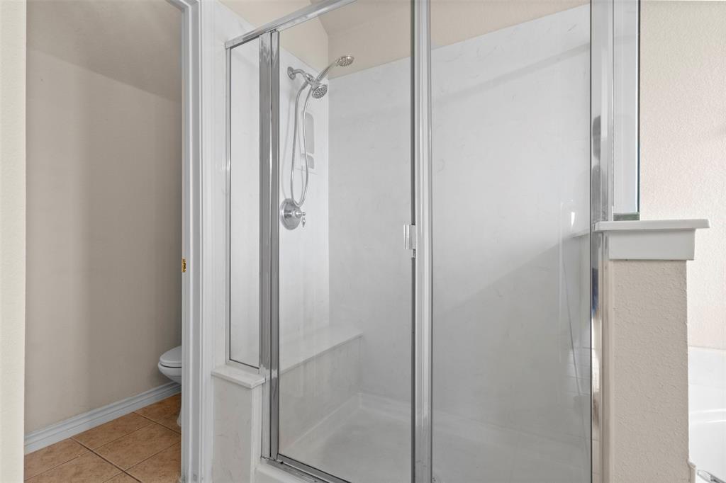 Walk-in shower featuring a chrome-framed glass enclosure, handheld showerhead, integrated seating, and surround wall paneling