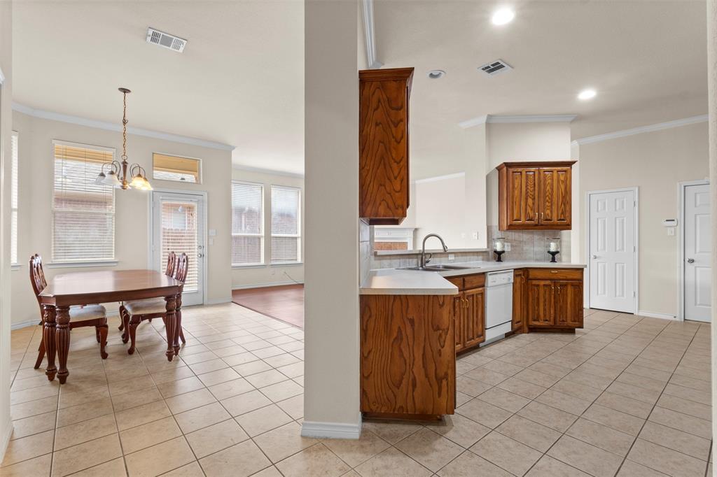 Kitchen featuring stained wood cabinetry, solid surface countertops, and white appliances, complemented by tile flooring and crown molding