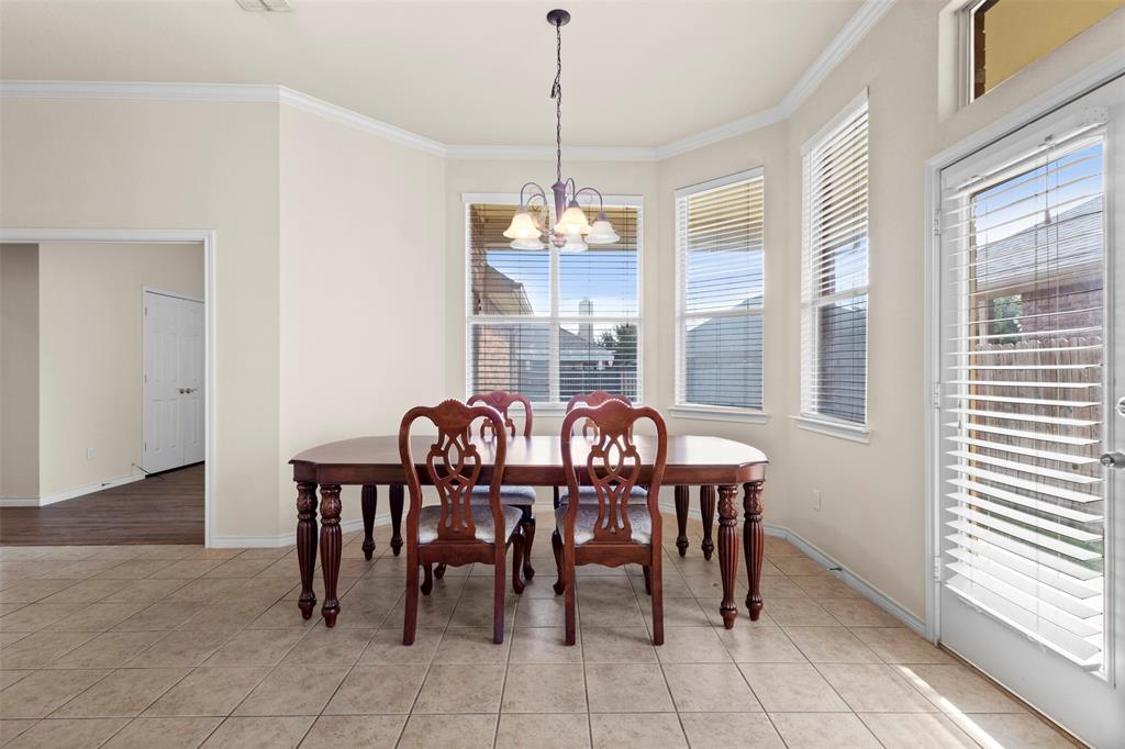 Dining area featuring tile flooring, crown molding, a multi-light chandelier, a bay window configuration, and a glass-paneled exterior door