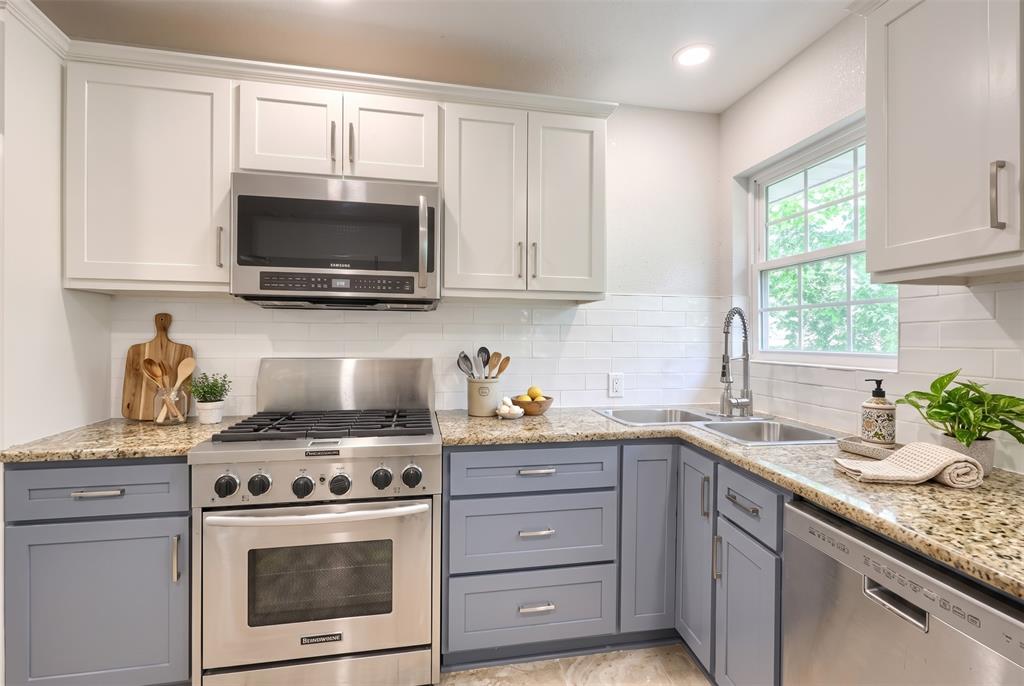 Kitchen featuring two-tone cabinetry, stone countertops, subway tile backsplash, stainless steel appliances, and a gooseneck faucet