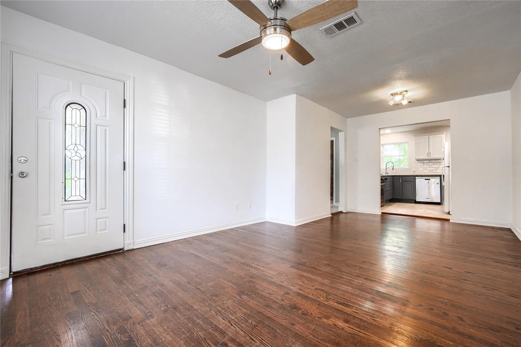 Interior space featuring wood-finish flooring, white walls, and a ceiling fan with integrated lighting