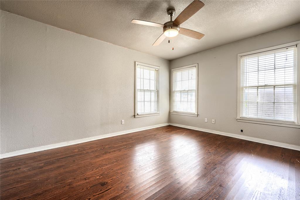 Interior space featuring wood-finish flooring, three double-hung windows, and a ceiling fan with integrated lighting