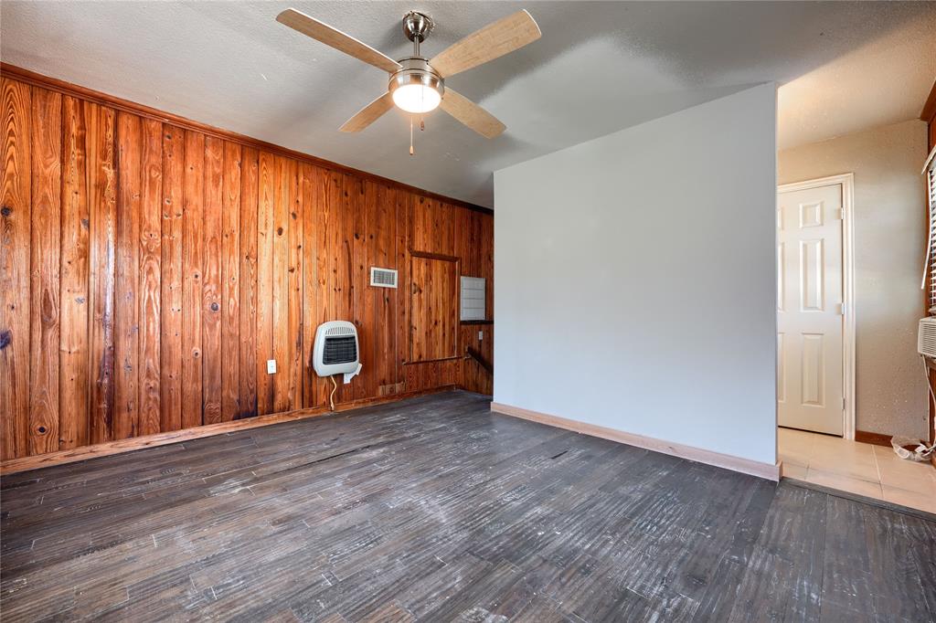 Interior space featuring wood-paneled walls, wood-finish flooring, and a ceiling fan with integrated lighting