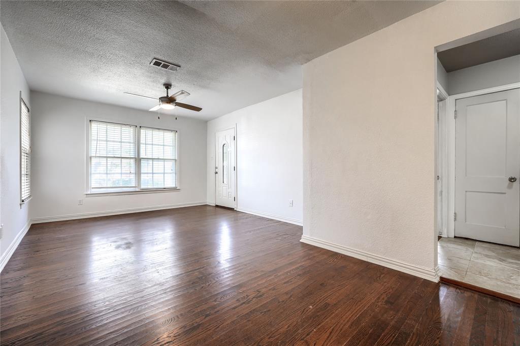 Interior space featuring dark-stained wood flooring, multi-pane windows, a central ceiling fan with integrated lighting, and a paneled entry door