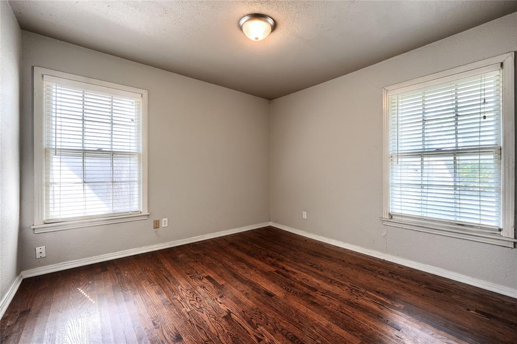 Room featuring wood-finish flooring, dual windows with fitted blinds, and a flush-mount ceiling light fixture