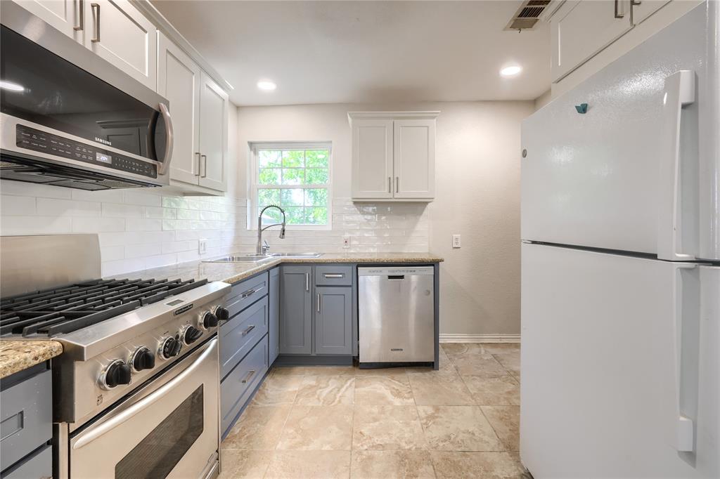 Kitchen featuring stone-finish countertops, subway tile backsplash, stainless steel gas range, built-in dishwasher, and stone-finish flooring
