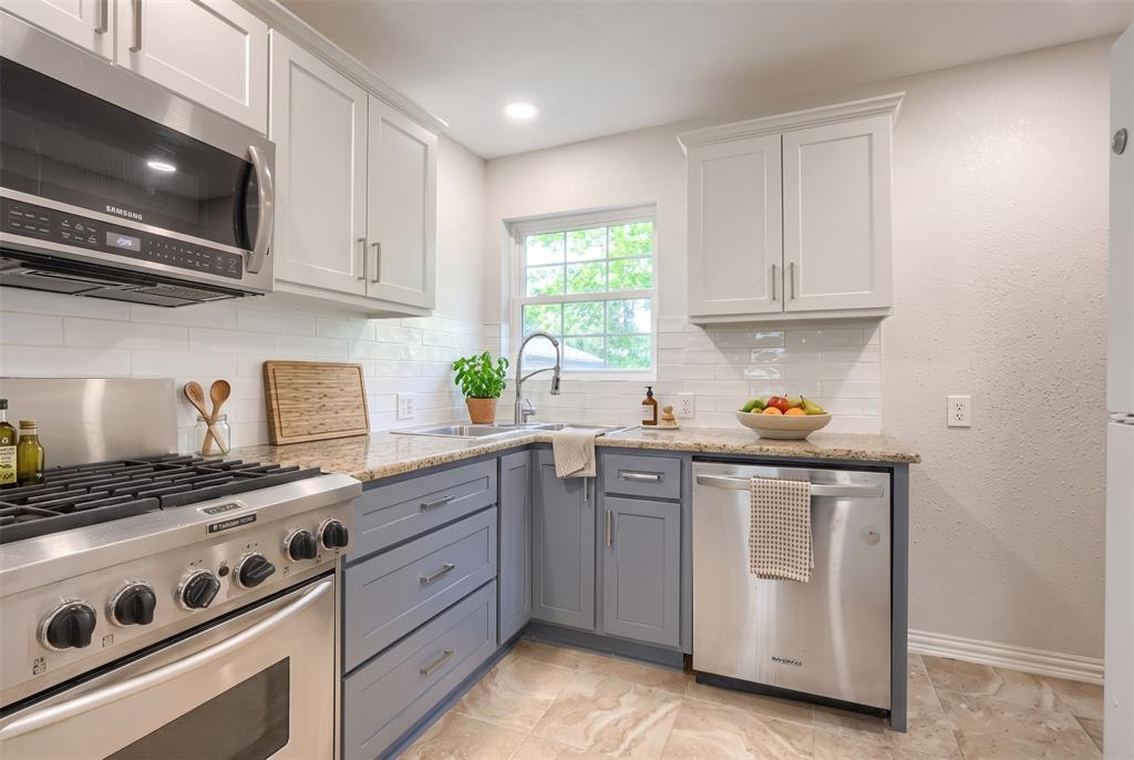 Kitchen featuring two-tone shaker-style cabinetry, stainless steel appliances, stone countertops, a subway tile backsplash, and a stainless steel undermount sink