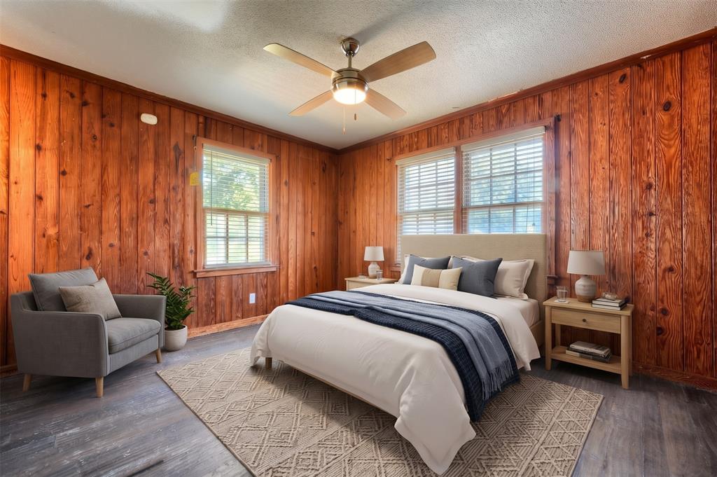 Room featuring warm-toned wood-paneled walls, wood-finish flooring, and a multi-blade ceiling fan with integrated lighting