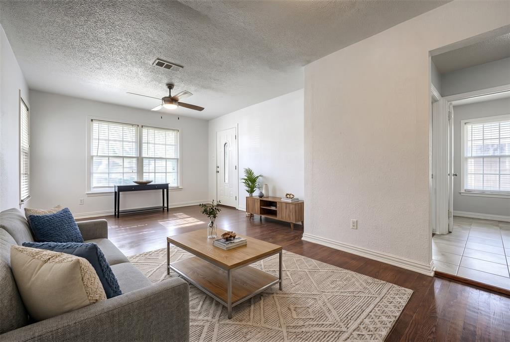 Neutral interior featuring wood-finish flooring, textured ceilings, dual-pane windows, and a ceiling fan with integrated lighting