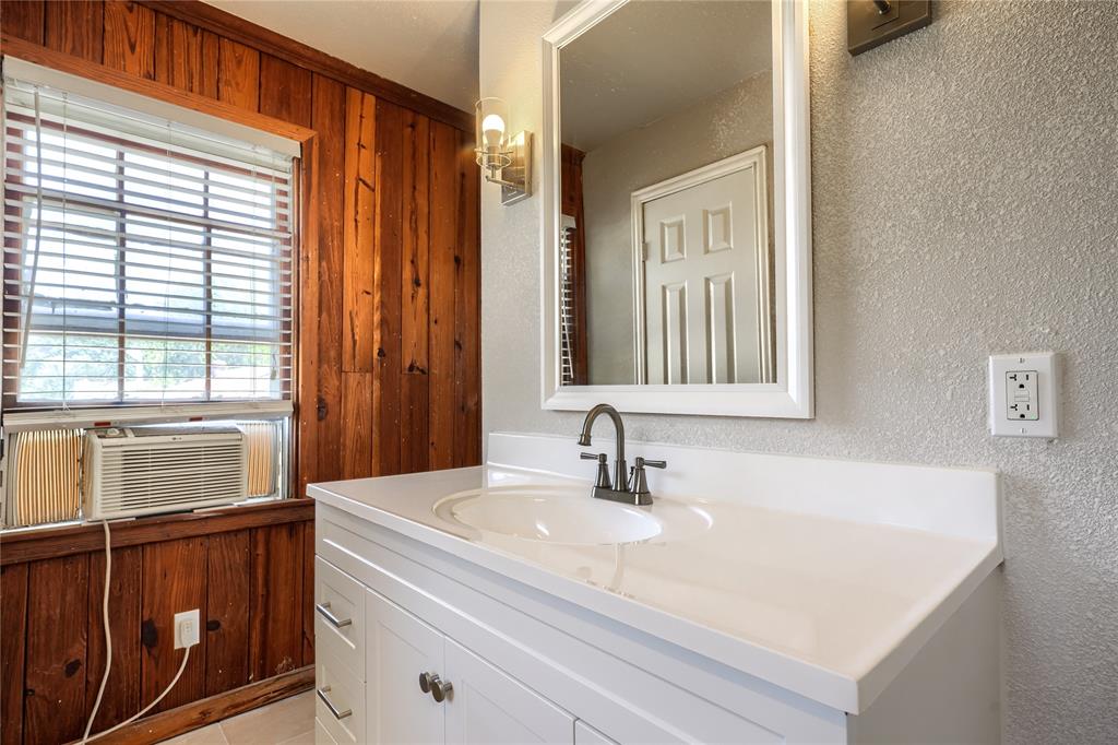 White vanity with a molded countertop and integrated basin, equipped with a metal dual-handle faucet and mounted rectangular mirror
